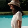 Femme de profil portant le T-Shirt Femme 100% Coton BARRY Emile et Ida crème, en extérieur au bord d’une piscine.