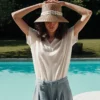 Femme portant le T-Shirt Femme 100% Coton BARRY Emile et Ida crème, bras levés et chapeau de paille.