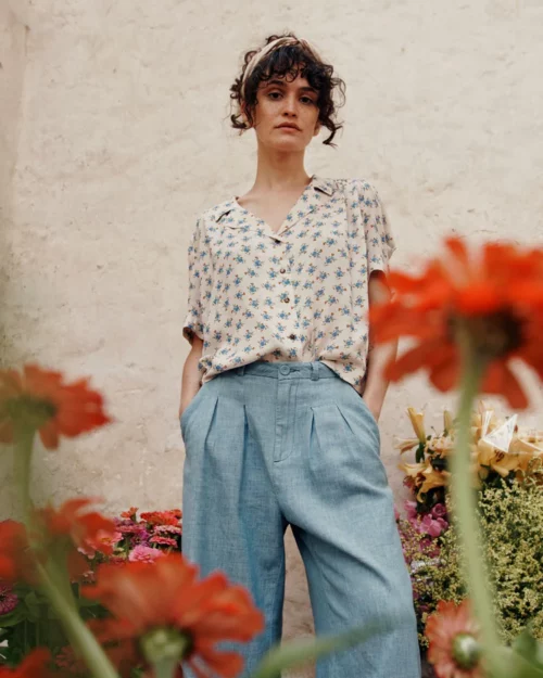 Femme portant la Blouse écru fleurs bleues en viscose BOÉMIE Emile et Ida, associée à un pantalon large en toile bleu clair.