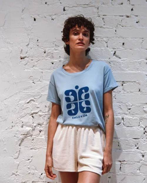 Femme portant le T-Shirt Femme Coton Bio BORIS Emile et Ida bleu ciel, associé à un short en tissu éponge crème.