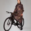 Poncho de pluie. Poncho Rainkiss. Vu porté. Couleur marron. Motif léopard. Vêtement imperméable. Vu porté sur un vélo. RAINKISS Poncho Léopard foncé.